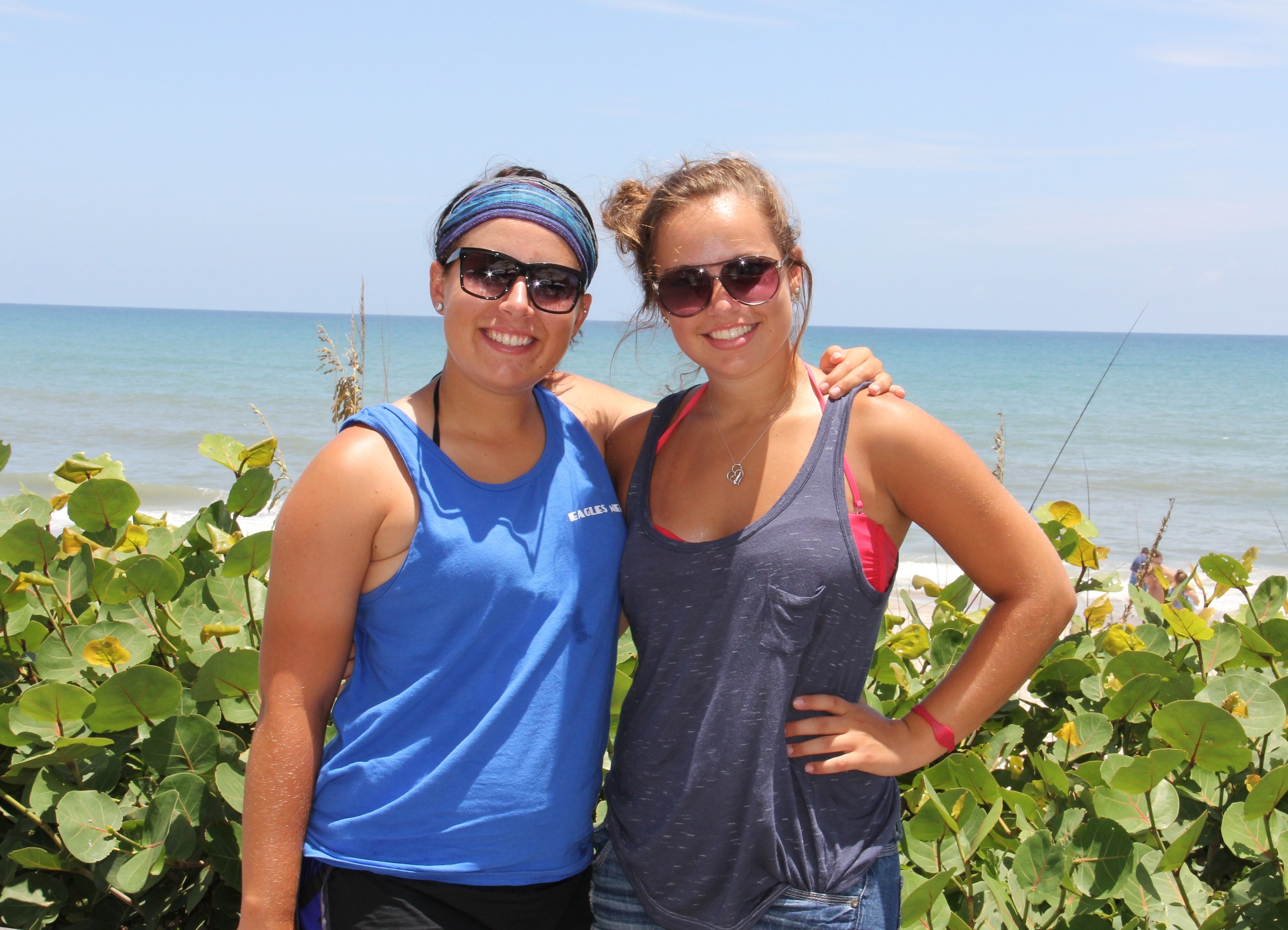 two women standing next to each other on a beach
