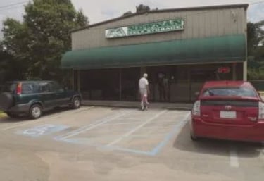 Newnan Self Storage facility building with a green awning and cars in a parking lot.