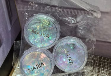 Three jars of iridescent MAJKA chunky glitter flakes for nail art in a clear plastic bag.