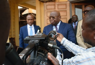 Professional videographer filming a news interview with African politicians in blue suits.