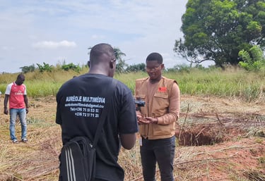 A videographer filming a man inspecting soil at a rural agricultural site for Aureole Multimedia.