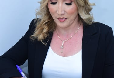 Professional businesswoman in a black blazer signing a formal document with a blue pen.