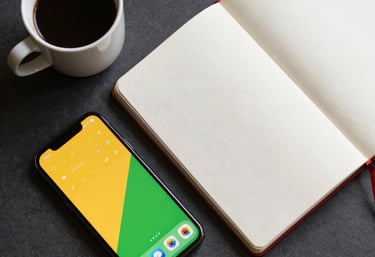 An artistic overhead shot of a clean workspace with a notebook, a cup of coffee, and a smartphone displaying a yellow and green app interface.