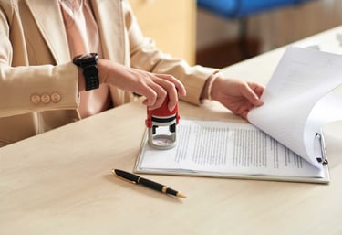 a woman in a suit and a watch on her wrist notarizing a document