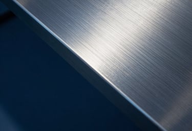 Abstract photography of light hitting a metal surface, creating reflections in navy blue and steel blue. Symbolic of precision, engineering, and modern efficiency.
