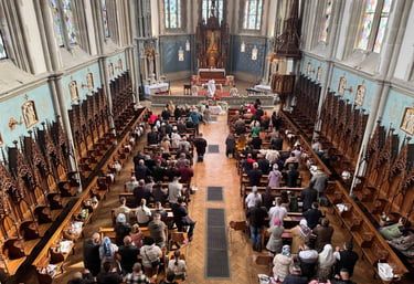 Congregation attending a mass inside a gothic revival church with ornate wood carvings
