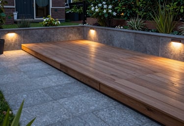 A professional photo of a freshly renovated Dutch garden with a luxury wooden deck, sleek grey stone pavers, and modern outdoor lighting at twilight.