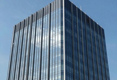 Clean and professional photography of a modern South American commercial office building with glass facade reflecting a clear blue sky, elegant and professional mood.