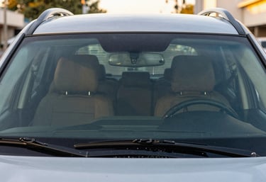 A modern SUV with a flawless new windshield reflecting a bright North American / US cityscape during the golden hour, symbolizing safety and clarity.