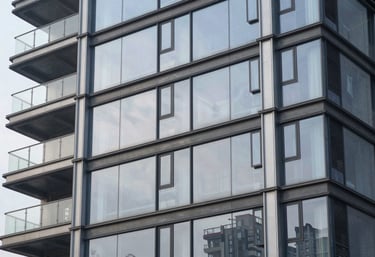 A finished commercial development project, featuring a modern glass facade reflecting a pale mist sky, showing craftsmanship.