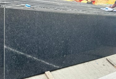 Polished black granite slabs stacked at a warehouse for kitchen countertops and flooring.