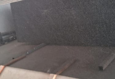 Polished black granite slabs with a mirror finish for kitchen countertops and flooring.