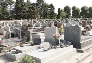 Granite tombstones and memorial monuments with fresh flowers in a peaceful cemetery landscape.