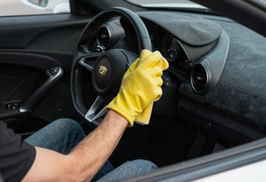 Close-up of a professional cleaning the interior of a luxury car with microfiber cloth.