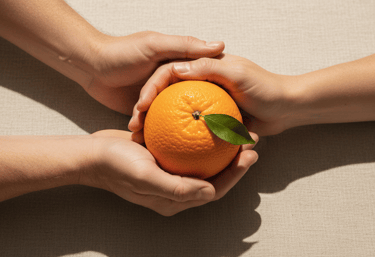 Manos sosteniendo naranja simbolizando confianza y trato cercano