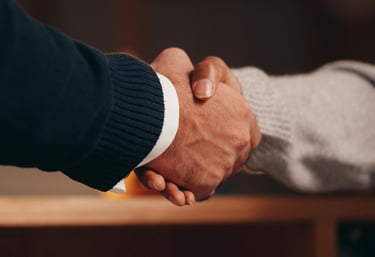 Close-up of a firm professional handshake between two business partners in an office setting.