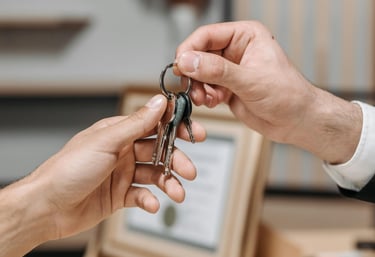 A real estate agent handing house keys to a new homeowner after a successful property sale.