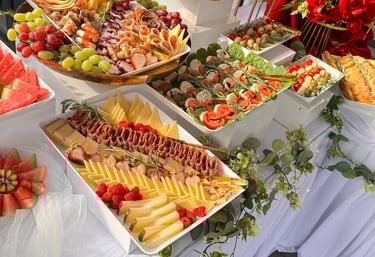 Mesa de catering gourmet con tablas de embutidos, tablas de quesos, brochetas caprese y aperitivos 