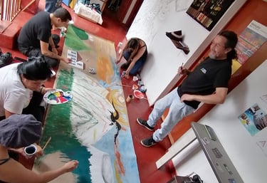 Artistas y estudiantes colaborando en un gran mural comunitario de paisaje en un estudio de arte