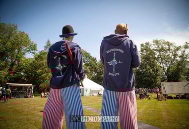 Two performers in striped pants and branded hoodies entertain crowds at an outdoor festival.