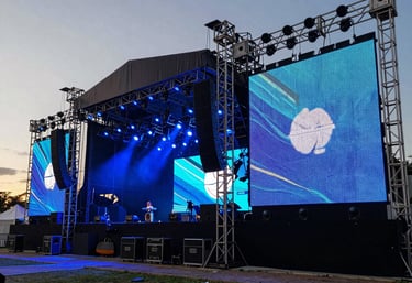 Professional photography of a large outdoor stage setup at sunset in Brazil, featuring high-end audio equipment and massive LED screens, steel blue atmospheric lighting.