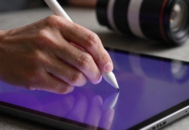 A close-up shot of a designer's hand using a stylus on a high-definition tablet, with royal amethyst light reflecting off the screen.