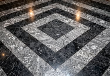 High-angle shot of a polished marble hallway floor with a geometric pattern of charcoal black and silver grey tiles, reflecting overhead lights.