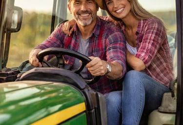 Ένας ανδρας και μια γυναίκα αγρότες χαρούμενοι πάνω στο τρακτέρ τους