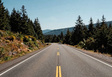 A scenic view of a clean highway winding through a Pacific Northwest landscape under a clear sky, North American / US, wide-angle lens.