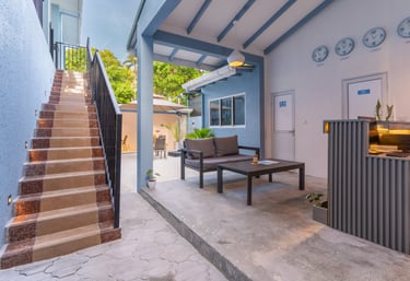 Modern hotel reception area with outdoor lounge seating, front desk, and stone stairs.