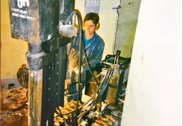 A technician operating a compact crawler mounted core drilling rig inside a building renovation site.