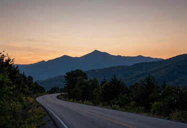 A scenic landscape photography of a winding rural road during sunset, with silhouettes of ancient Appalachian mountains in the distance, North American / US.