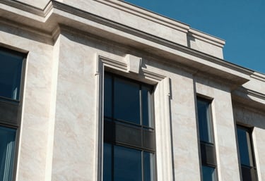 Architectural detail of a luxury European building. Sharp shadows on white stone walls, deep blue glass, and elegant metallic accents under a clear Spanish sky.