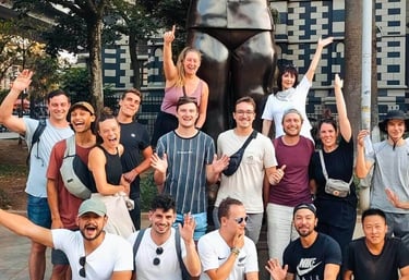 A group of happy travelers posing for a photo in front of the famous Botero statue in Medellin, Colombia.
