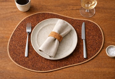 Rustic table setting with a natural cork placemat, ceramic plate, and linen napkin on a wooden surface.