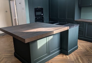 a dark green moody kitchen with a nice wooden counter top, with a side countertop of a marble
