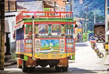 A colorful traditional Colombian chiva bus decorated with intricate folk art parked on a town street.