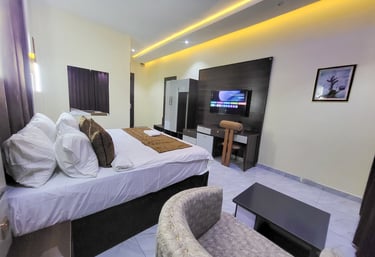 A warmly lit hotel room featuring modern furniture and a comfortable bed.