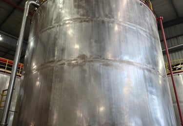 Low angle shot of a massive finished cylindrical industrial tank in a Mexican facility, shimmering metallic finish, professional industrial photography.