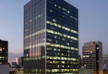 A photography of a modern Brazilian urban office building at dusk, with glowing windows. Represents the bustling environment of fintech and corporate growth.