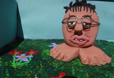 Surreal handmade clay sculpture of a head with glasses and bare feet on a floral background.