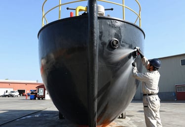 Close-up of a freshly painted ship hull glistening under sunlight at the dock.