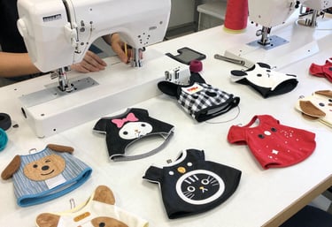 Una persona que utiliza una máquina de coser industrial para fabricar ropa y baberos para mascotas