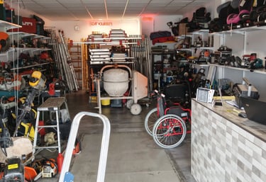 A well-stocked equipment rental shop featuring power tools, concrete mixers, and ladders on organized shelves.