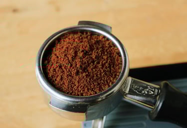 Finely ground espresso coffee beans in a stainless steel portafilter ready for brewing.