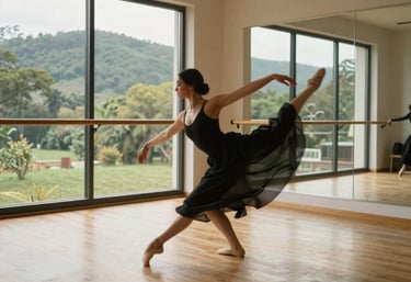 An elegant, airy dance studio with blonde wood floors and mirrors. A dancer moves through a contemporary pose, blurred to emphasize flow. Outside the windows, a lush North American landscape is visible.