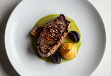 An overhead food photography shot of a gourmet entree beautifully plated on a white ceramic dish. Clean composition with natural lighting, showcasing culinary excellence.