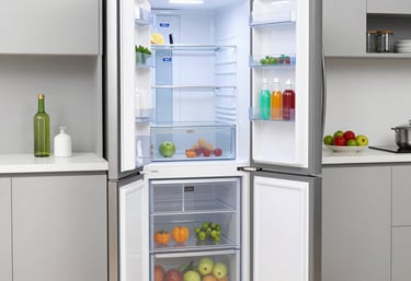 Technician repairing a modern stainless steel refrigerator in a bright kitchen.