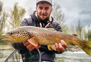 Pescador mostrando una trucha capturada en un río de León durante jornada de pesca deportiva
