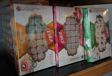Boxes of Esra brand Turkish Delight in rose, fruit, and pistachio flavors on a shelf.